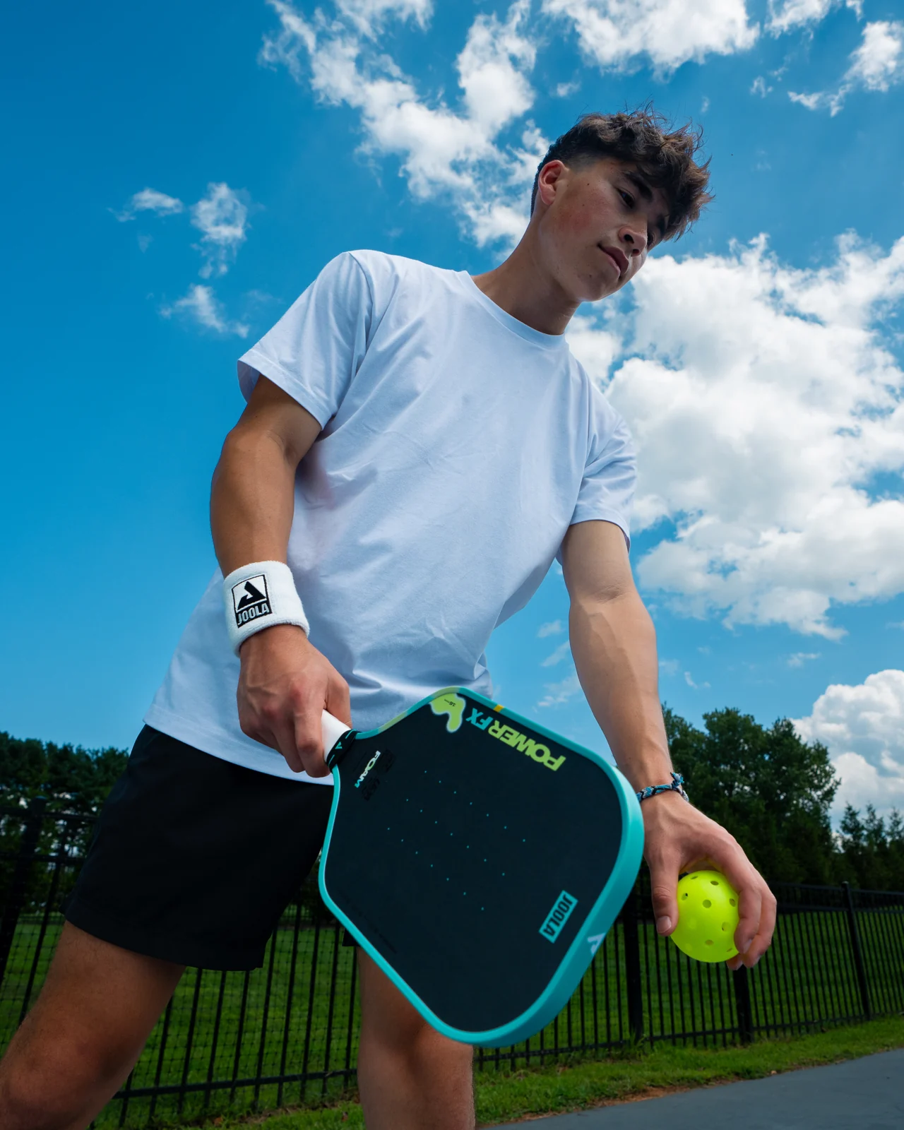 Tay vợt nam cầm JOOLA Power FX Daydream và bóng pickleball trên sân